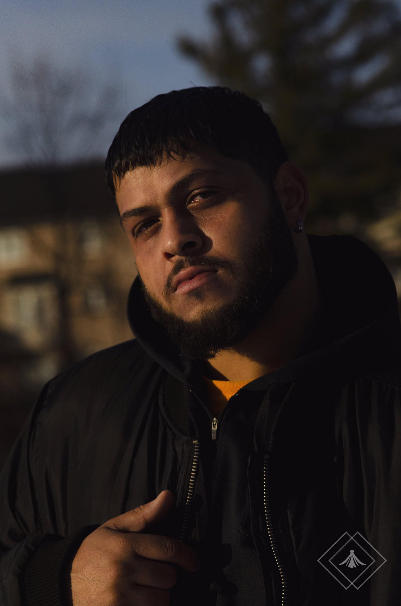 Amid the blinding light, a man of colour struggles to peer past it, his gaze directed towards the camera.
