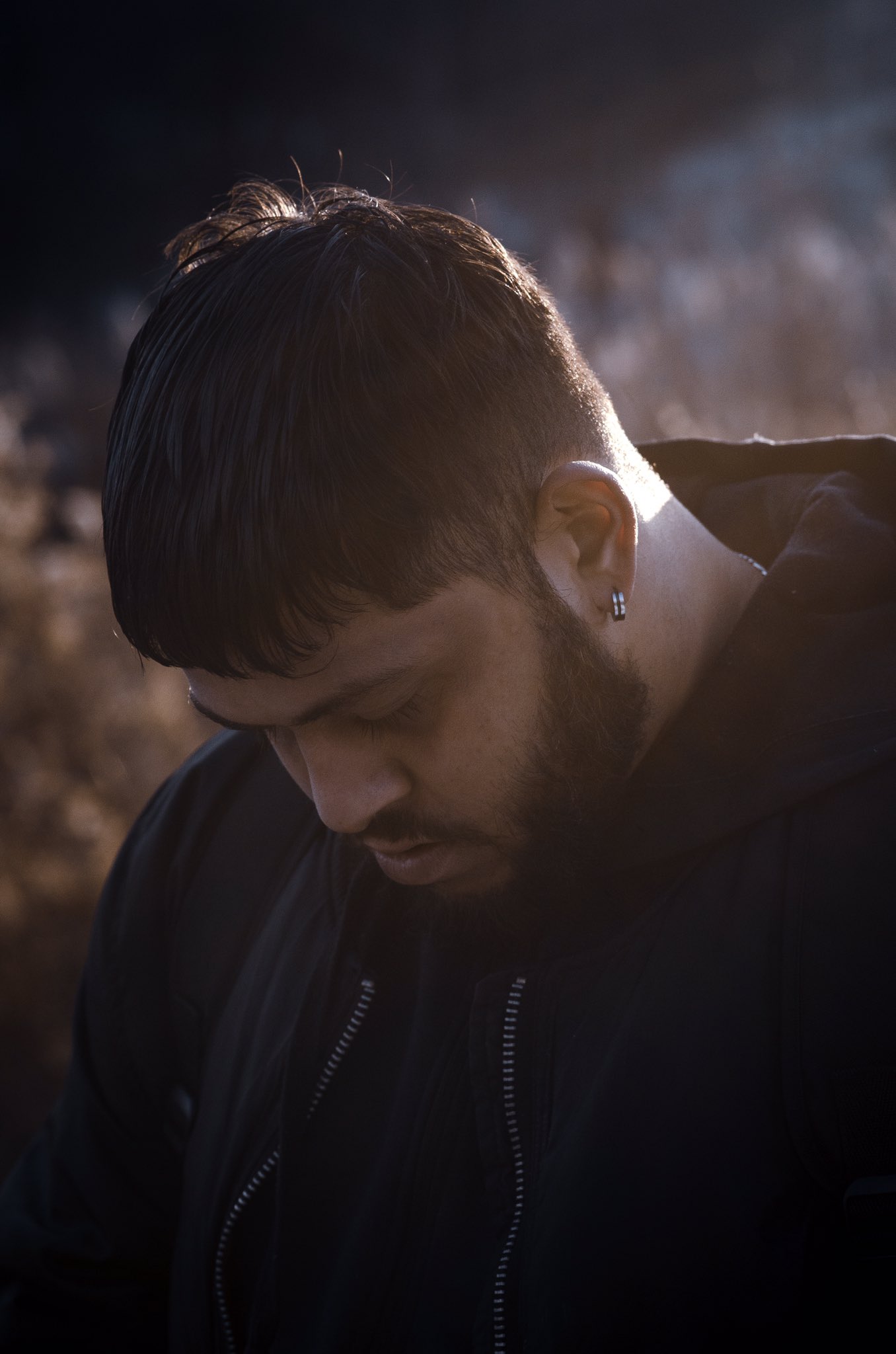 The sun peeks through at just the right angle, meeting a man’s gaze as he looks down toward the floor.